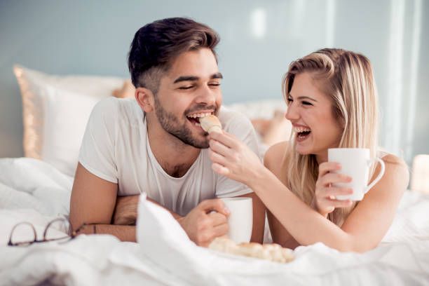 Cute couple having breakfast in bed in the bedroom.